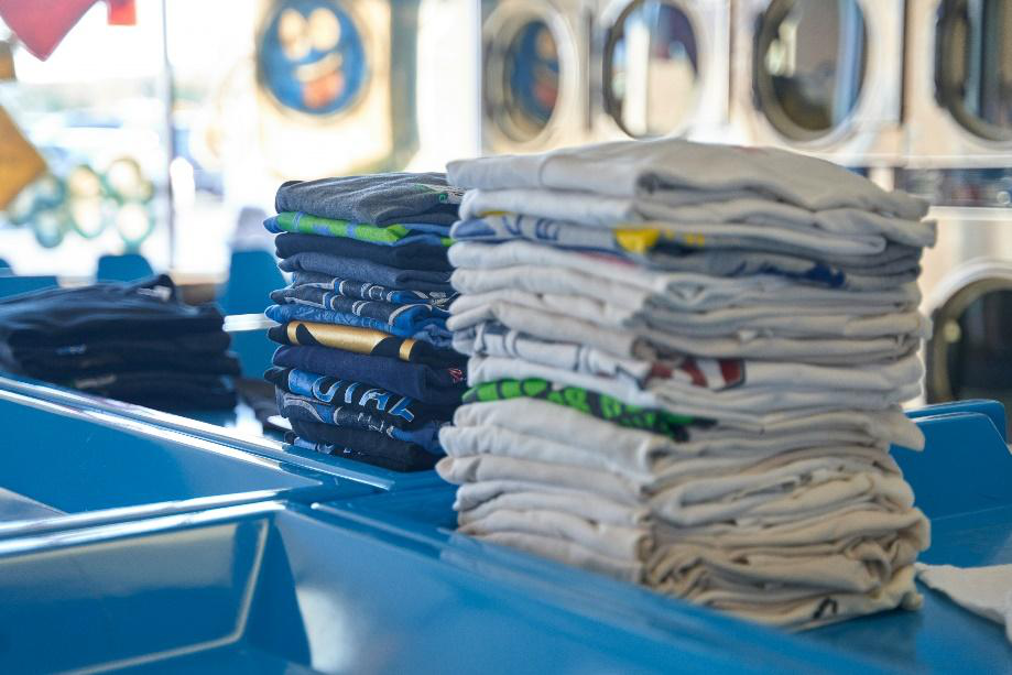 A neatly folded stack of shirts on a blue table