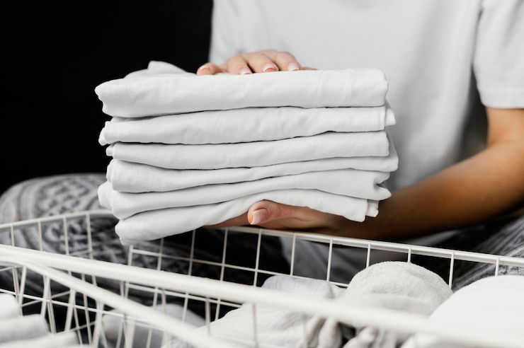 A person holding a set of neatly folded clothes