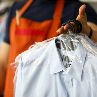 A person holding clothes covered in plastic