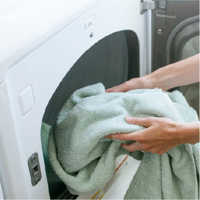 A person putting a towel inside a washing machine
