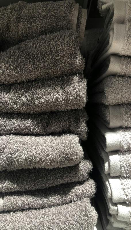 Neatly folded white towels stacked for commercial use in salons or fitness centers